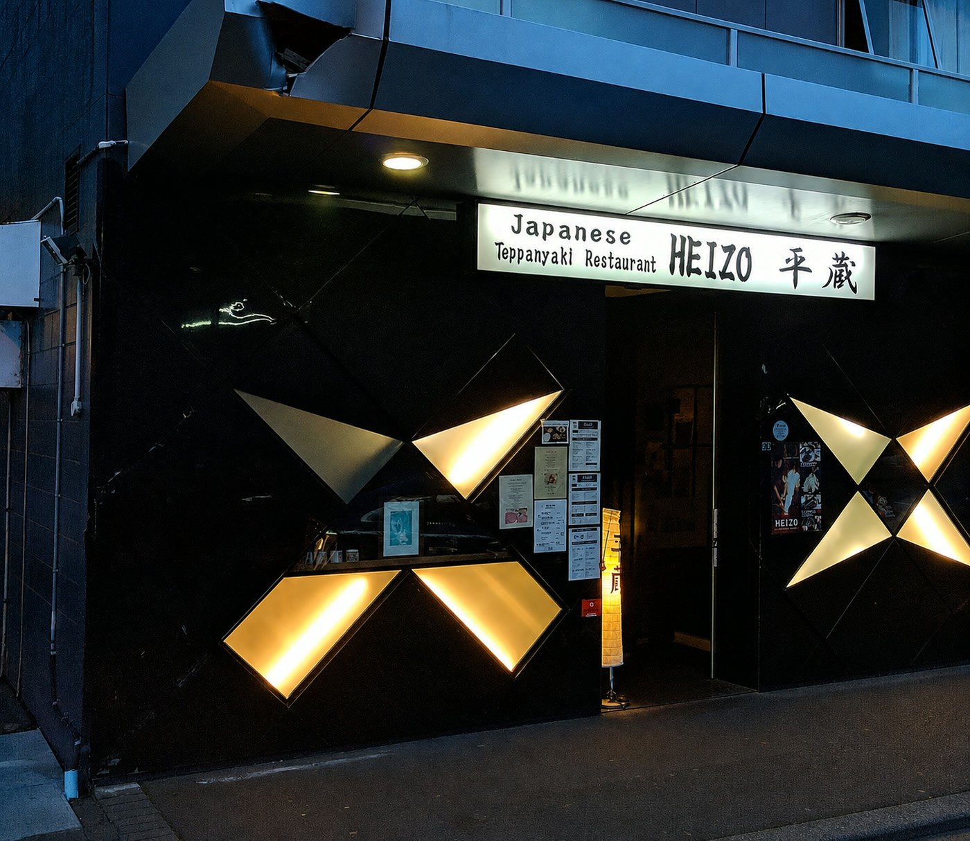 The lit shopfront of HEIZO Teppanyaki Japanese Restaurant on Short Street, Newmarket, with its illuminated cross-panel facade and the sign reading Japanese Teppanyaki Restaurant HEIZO 平蔵