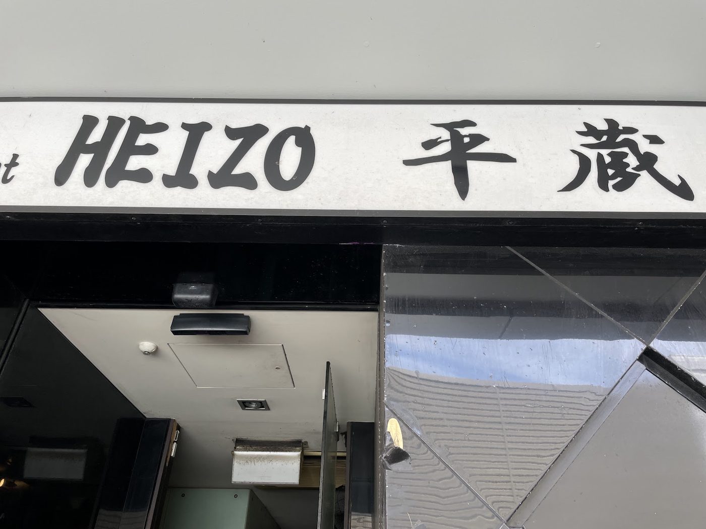 Close-up of the HEIZO 平蔵 sign above the restaurant's entrance in daylight